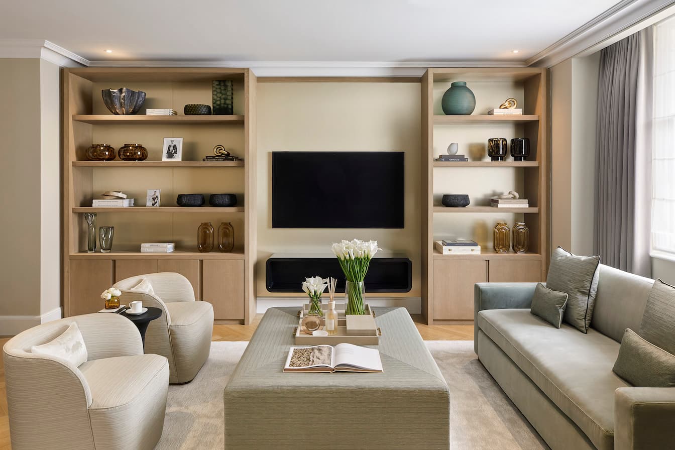 A bespoke media wall with an electric fire under the TV mounted on the wall and shelving either side
